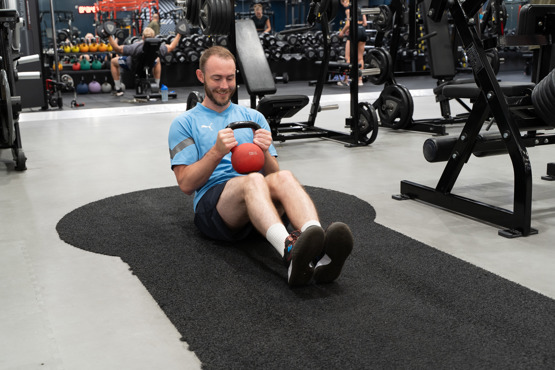 Man på gym gör russian twist