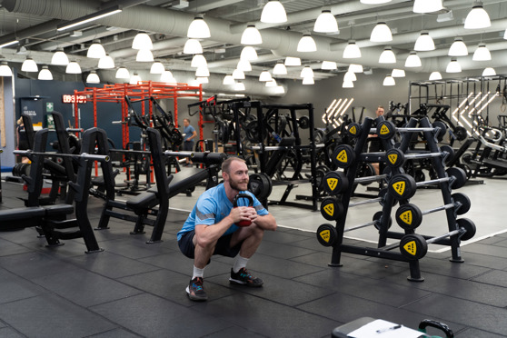 Man gör goblet squat med kettlebell