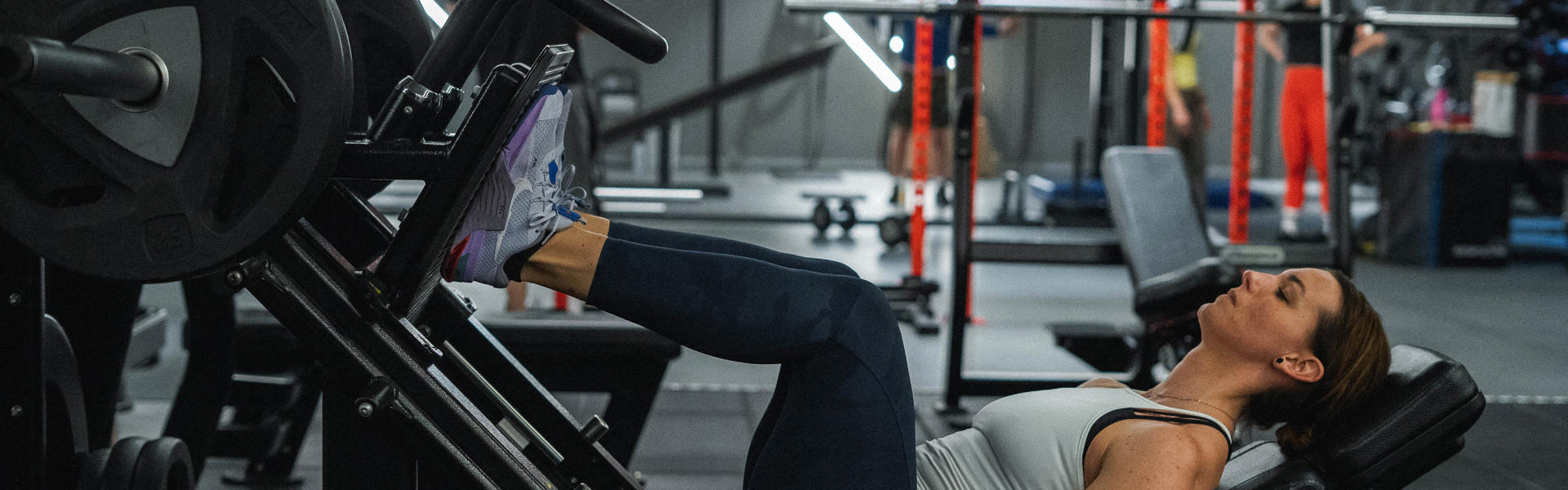 Kvinna träna ben i maskin på gymmet