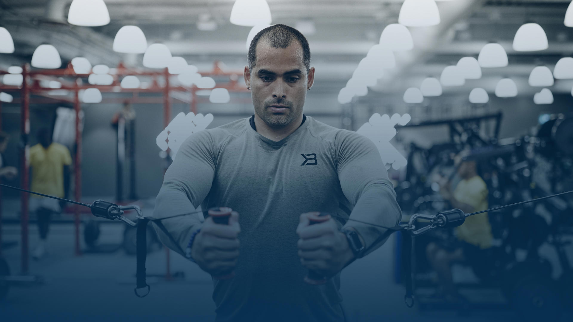 Muscle guy in gray shirt working out in a gym.
