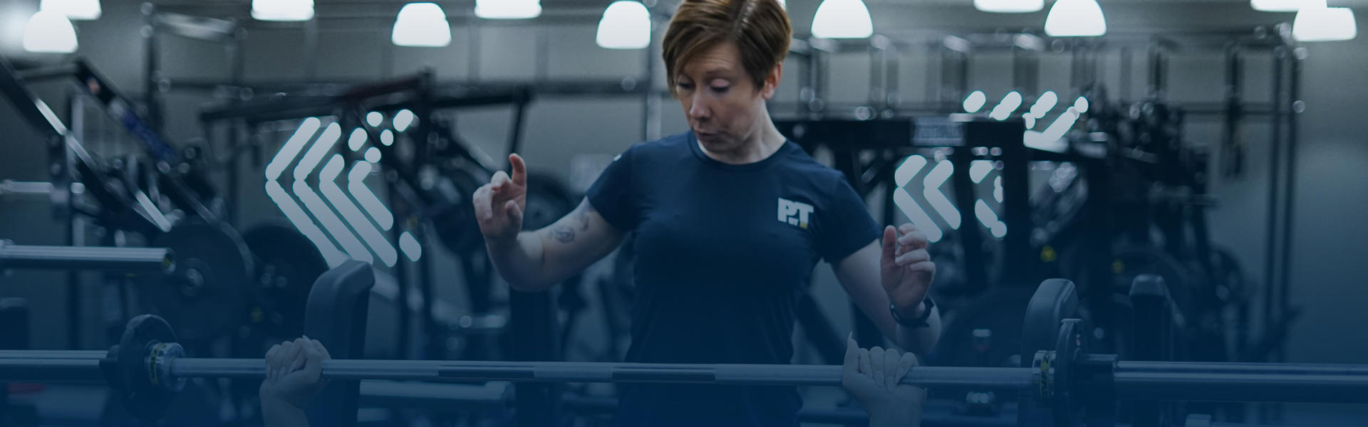 Woman PT standing above client helping them with the benchpress.