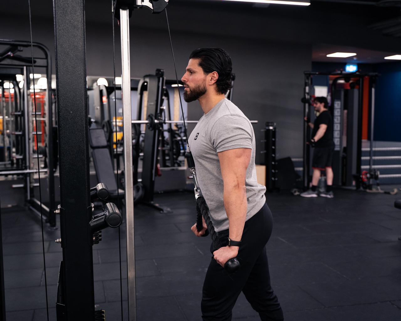 Man i slutposition av triceps pushdowns – armarna fullt utsträckta nedåt med aktiverad triceps