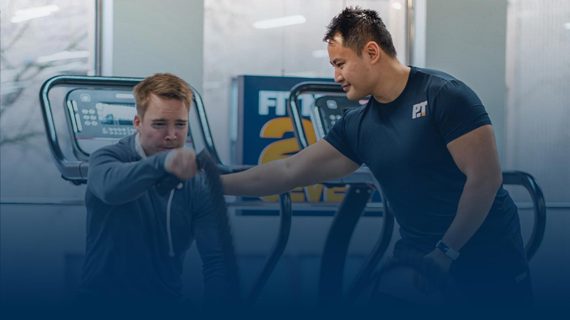 PT helping guy at gym to workout with a rope.