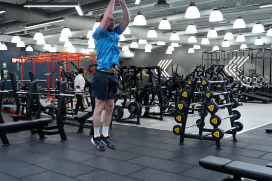 Man på gym hoppar upp i Burpee