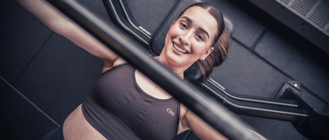 Glad tjej på gymmet som kör bänkpress