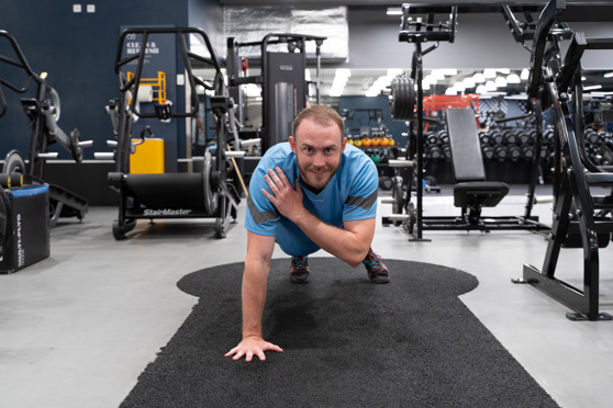 Man på Gym Utför Plankan med Armtouch