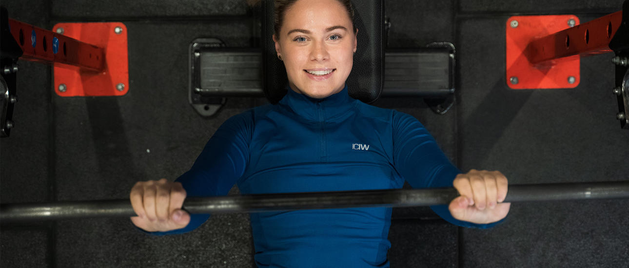 Kvinna kör skivstång liggande på gymmet