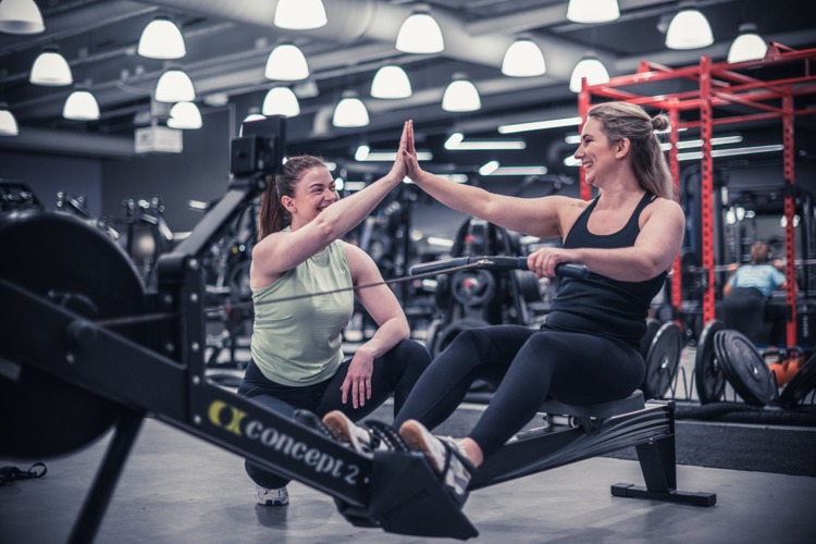Två glada tjejer som gör high five på gymmet