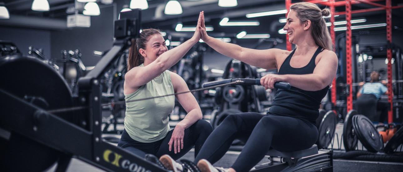 Två glada tjejer som gör high five på gymmet