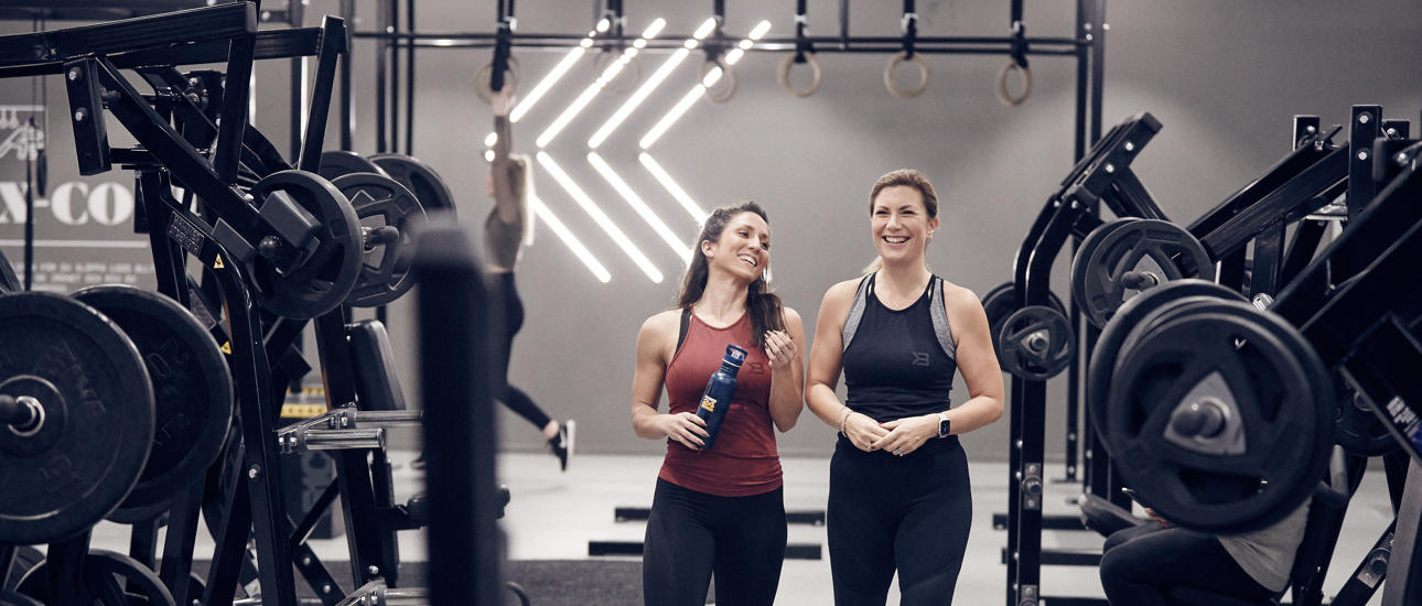 Två glada kvinnliga medlemmar på gymmet