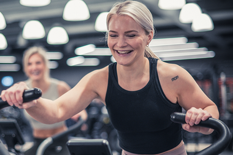 Två glada tjejer på cardiomaskiner