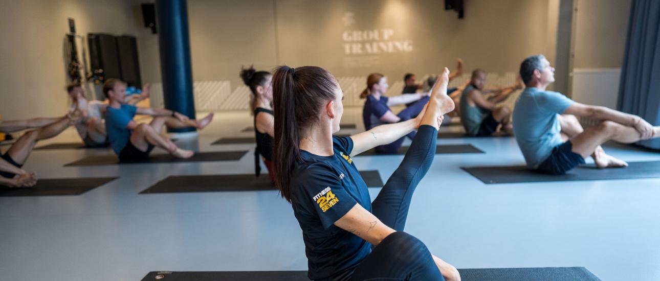 Pilates gruppträning på Fitness24Seven med instruktör i förgrunden med rakt ben