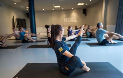 Pilates gruppträning på Fitness24Seven med instruktör i förgrunden med rakt ben
