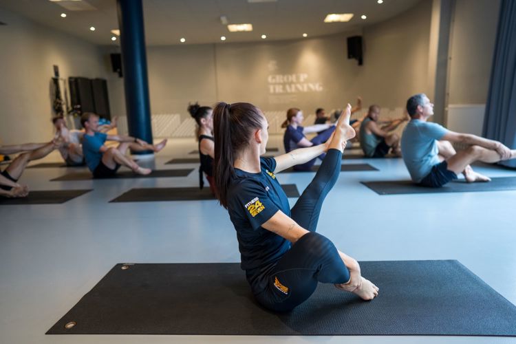 Pilates gruppträning på Fitness24Seven med instruktör i förgrunden med rakt ben