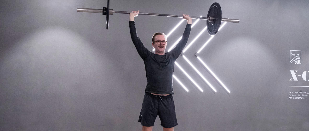 Man kör funktionell press med skivstång på gymmet